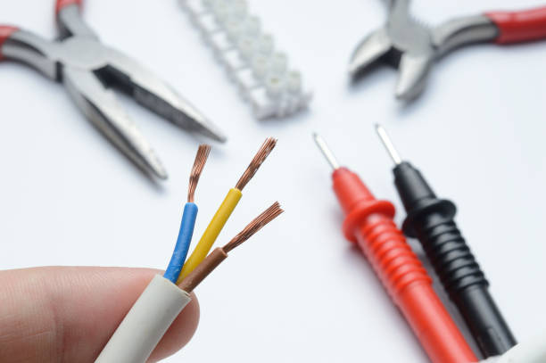 istock stripped, electrical three-core wire in hand against the background of terminal blocks and tools. close-up. 1363107915