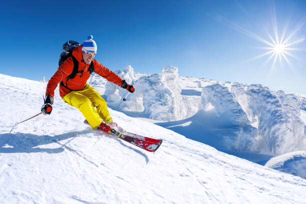 ski alpin skifahren in den bergen gegen blauen himmel - abfahrtslauf stock-fotos und bilder