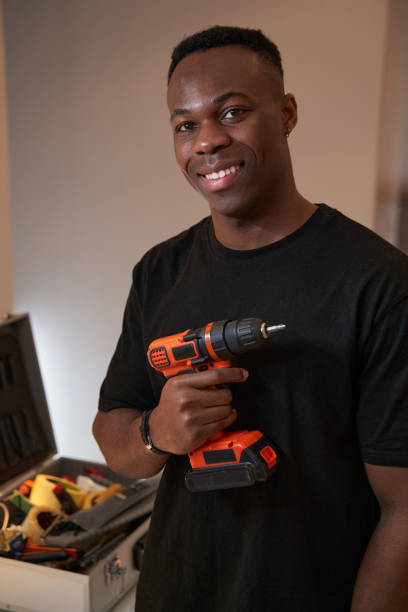 istock Male smiling to camera while holding power drill 1363110351