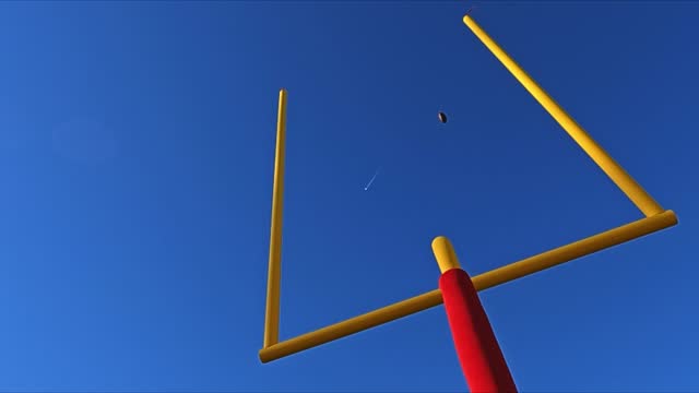 Looking up at a field goal during an American football game in slow motion
