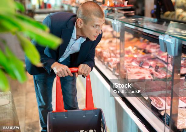 Focused Man Examines The Production In The Department Of The Butcher Shop In The Supermarket Stock Photo - Download Image Now