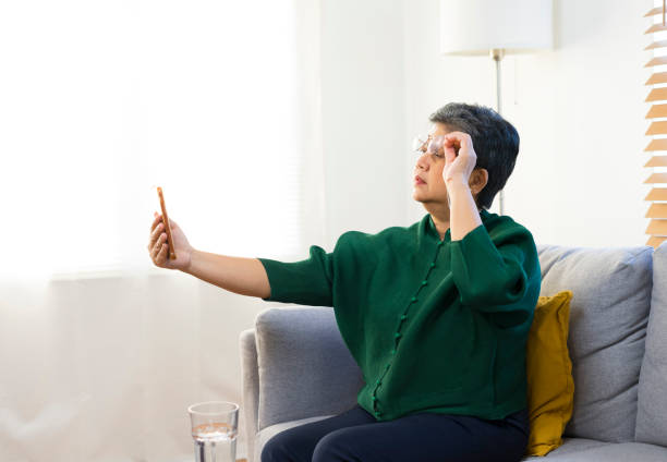 Elderly woman squinting while looking at smartphone screen, trying to read message.