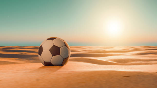 el sol brilla en el balón de fútbol en un desierto - beach football fotografías e imágenes de stock