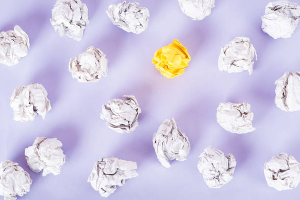 istock overhead shot of crumpled paper in oder and yellow one standing out on Very Peri background. great idea concept 1363114699