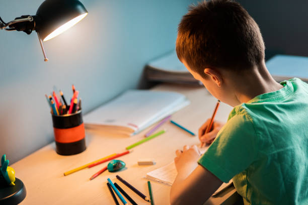 istock Boy sitting at the desk doing homework at home. 1363118714