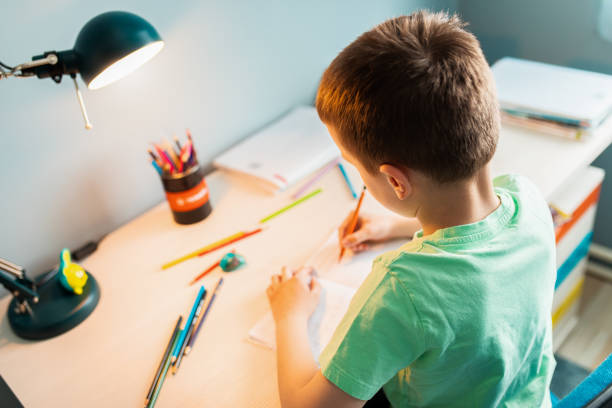 istock Boy sitting at the desk doing homework at home. 1363118730
