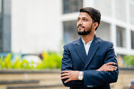 Outdoor Portrait of young Asian /Indian businessman wearing formal dress and looking at camera.