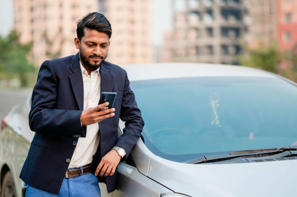 istock Young businessman using mobile phone while standing in front of his car. 1363118897