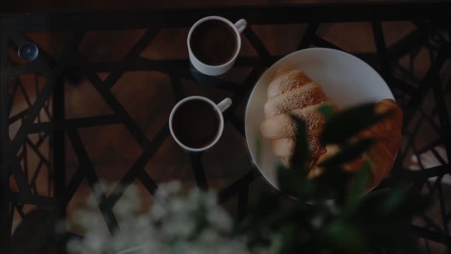 Woman is puttin on the table coffee cup. Fresh Сroissants. Good morning and wake up. Cozy moody, weekend  and relax at home. Tasty sweet breakfast.