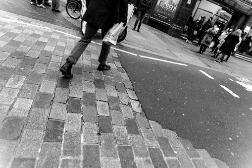 Street photography with Dutch angle of a man caarying a bag whilst crossing the street towards Russell Square Tube station. London, England, UK.