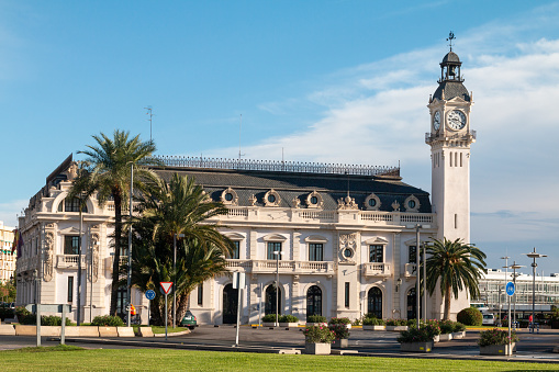 Clock Tower of the Port Authority Harbour Office in Valencia, Spain, with cars and commercial buildings visible.
