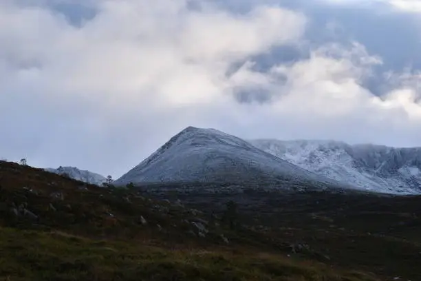 The tip of a mountain which appears to be covered in snow with a cloudy sky.