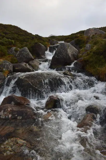 A small waterfall created near the top of a mountain, the water can be seen in motion as it heads down towards the camera.