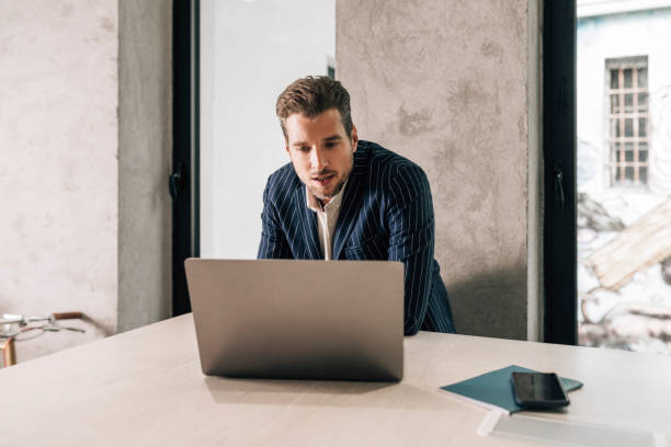 istock Elegant Businessman in a Suit Working at a Standing Desk, Using his Laptop 1363123403