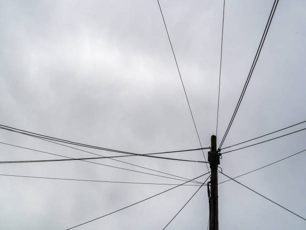 Telegraph pole with many phone wires, cables, urban street Engand, UK. Winter grey sky.