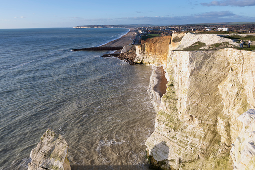 Seaford, UK - Jan 5, 2022: The view from the cliffs at seaford head, looking down to the beach at Seaford with tourists and holidaymakers on the beach in the distance, Seaford is on the south coast of England, in East Sussex, Sussex, England. It is a sunny day in winter.