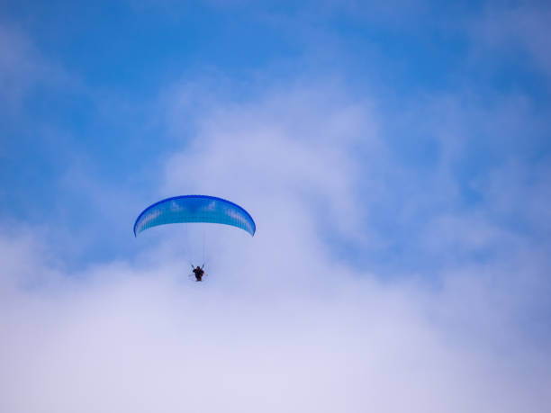 istock Unidentifiable blue paraglider against blue sky with clouds. UK. 1363127582