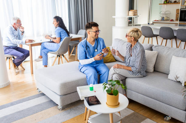 enfermera que habla con pacientes mayores mientras está en una visita domiciliaria. - atención residencial fotografías e imágenes de stock