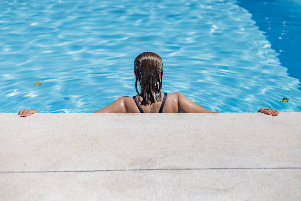 Madrid Spain. August 20, 2021. Middle-aged woman with her back turned inside a swimming pool