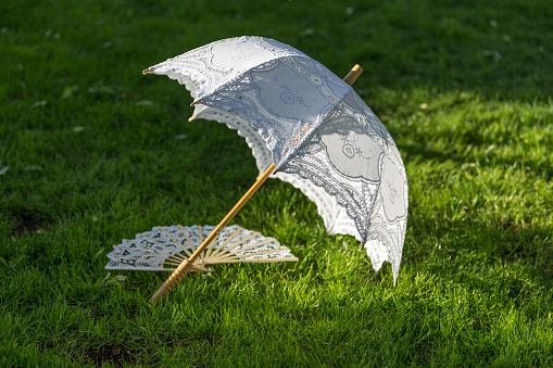 Madrid, spain may, 5 2018, White parasol and hand fan on garden grass