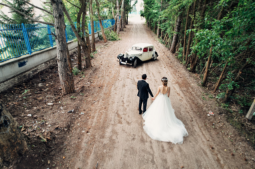 bride groom wedding photo taken with drone in front of classic car