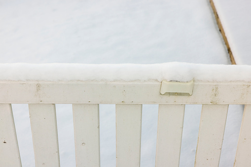 Close up view of white wooden fence covered with snow. Sweden.