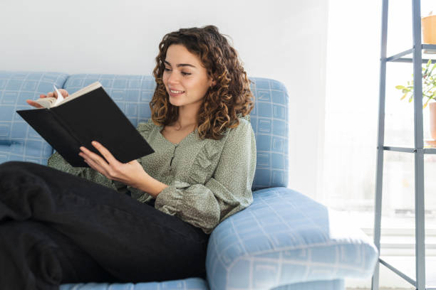 istock pretty curly haired woman reading a book at home 1363132786