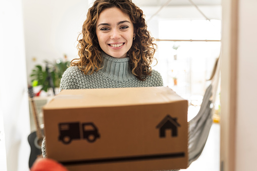 pretty hispanic curly haired woman receives a package at home