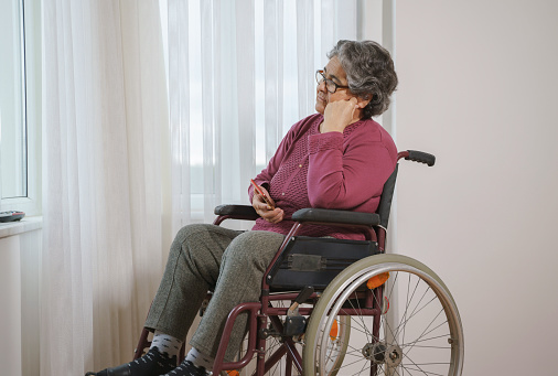 Senior woman sitting in wheelchair at home