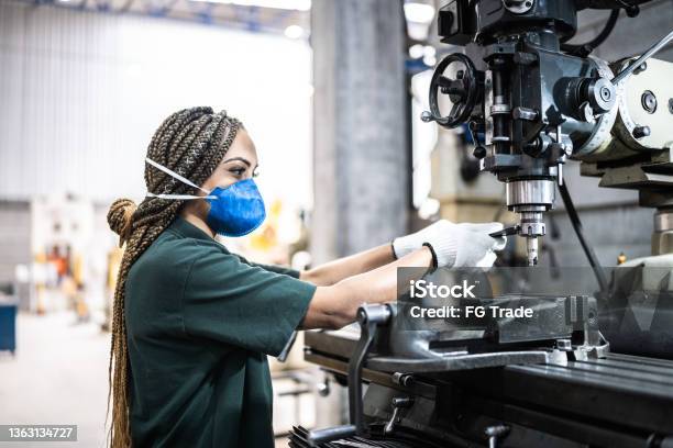 Mid adult woman working at a factory/industry - using a face mask