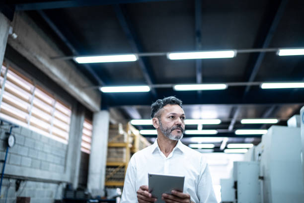 Mature businessman using a digital tablet in a factory Mature businessman using a digital tablet in a factory founder photos stock pictures, royalty-free photos & images
