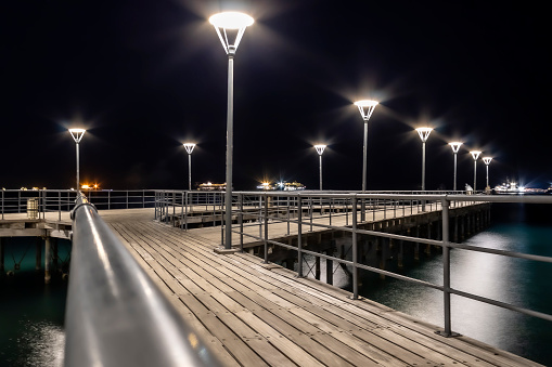 Illuminated sea pier at night with bright street lights