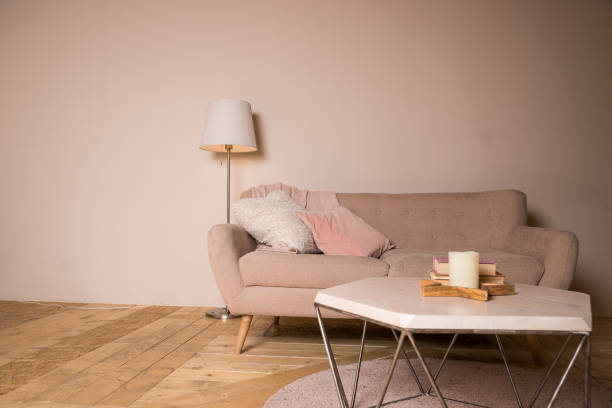 istock Small coffee table and candles next to designed sofa with pastel colored pillows.Still life details of nordic living room. bright living room interior. elegant sofa in living room with different fabrics cushions and a side table with a stylish lamp 1363142330