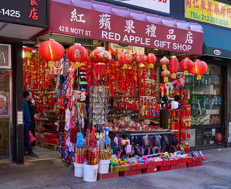 New York, NY - December 12, 2021: A Chinatown, Manhattan, NYC tourist gift shop selling traditional Chinese crafts and tourist novelties. Red Chinese lanterns hang from the awning and gifts in red plastic baskets sit on the sidewalk