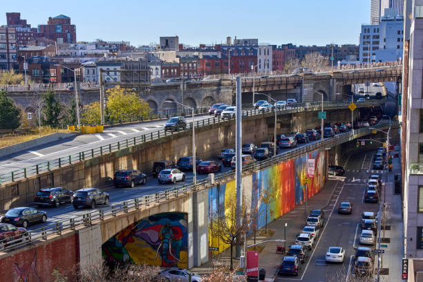 A colorful mural is painted on a retaining wall of the Brooklyn-Queens Expressway (BQE) in DUMBO, Brooklyn, NYC. Brooklyn, NY - December 12, 2021: A colorful mural is painted on a retaining wall of the Brooklyn-Queens Expressway (BQE) in DUMBO, Brooklyn, NYC. Beyond the highway traffic is the background is the entrance to the Brooklyn Bridge and Brooklyn Heights BQE stock pictures, royalty-free photos & images