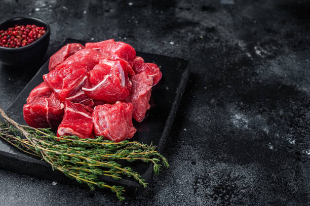 istock Raw diced red beef meat for Goulash on marble board. Black background. Top view. Copy space 1363145412