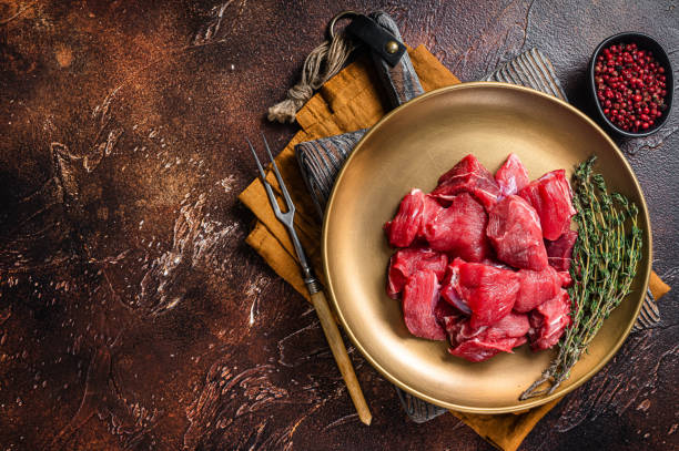 istock Raw diced lamb mutton meat with thyme. Dark background. Top view. Copy space 1363145432