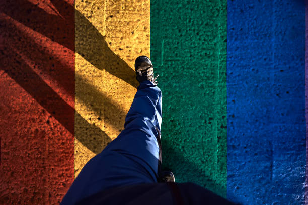 feet of man walking on asphalt with colors of the lgbt flag - design pride walking go imagens e fotografias de stock