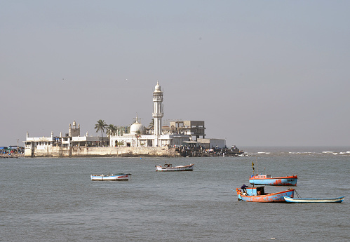 Haji Ali Mosque on an islet reached by causeway, Mumbai, Maharashtra, India. The white marble tomb and shrine of the Moslem saint Haji Ali sits just offshore in the Arabian Sea. Mumbai is the second most populous city in India built over seven islands and attracts poor people from all over India who beg and scrape a subsistence living in the face of great wealth from the indigenous Indian people and global tourists