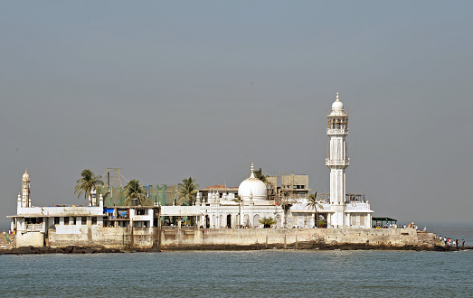 Haji Ali Mosque closeup on its islet reached by a causeway Mumbai, Maharashtra, India. The white marble tomb and shrine of the Moslem saint Haji Ali sits just offshore in the Arabian Sea. Mumbai is the second most populous city in India built over seven islands and attracts poor people from all over India who beg and scrape a subsistence living in the face of great wealth from the indigenous Indian people and global tourists