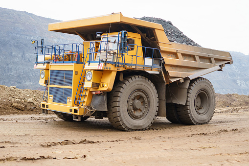 A large open-pit dump truck rides in an open-pit ore quarry. Part of the technological process of open-pit mining.