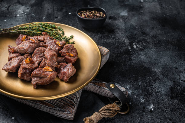 istock Chopped Grilled Diced Beef garlic steak on a plate with thyme. Black background. Top view. Copy space 1363146333