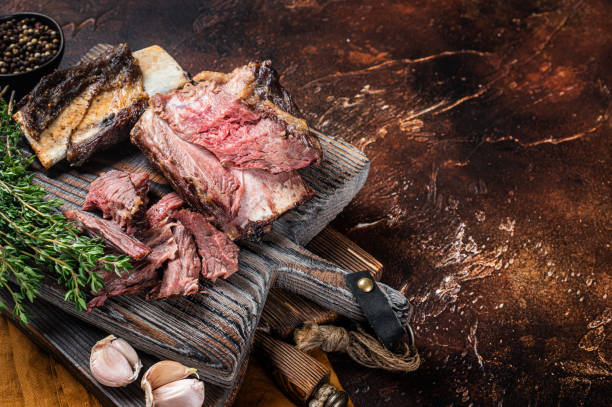 istock Braised veal beef short ribs on wooden cutting board with thyme. Dark background. Top view. Copy space 1363146384