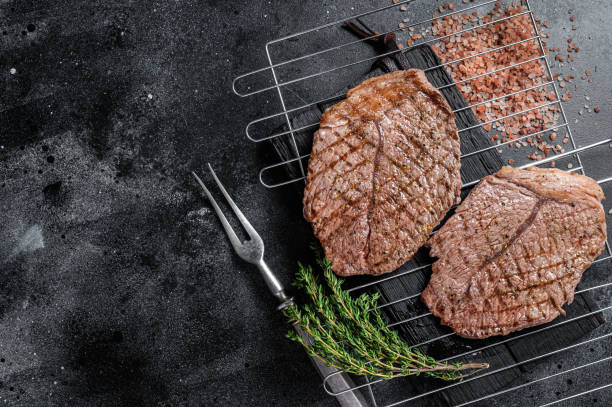 istock BBQ Grilled beef meat sirloin steaks on grill. Black background. Top view. Copy space 1363146474