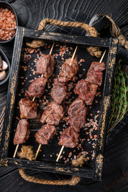 churrasco carne de bovino shish kebab espetos. fundo preto. vista superior - produto de carne - fotografias e filmes do acervo