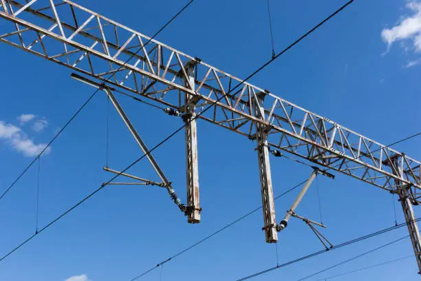 Photo of Railway electrification system. Power line wire over rail track. High metal construction transporting voltage energy.