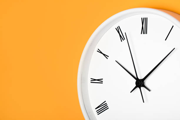 istock White round clock with black numbers isolated on orange color with shadow. 1363162228