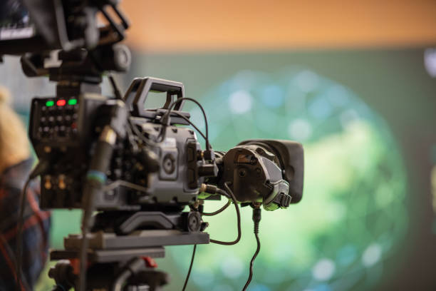 istock Modern broadcasting camera on a stand, ready to go live on an event. Back view of a video camera at a conference for live stream. 1363165394