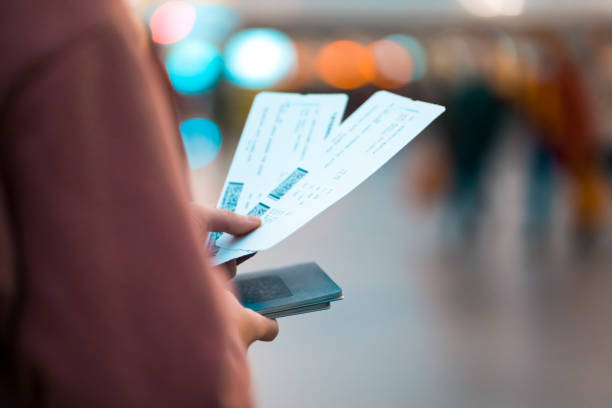 Girl holds tickets, boarding passes for a flight. A young girl is going on a trip, holds plane tickets in her hands and goes to check-in, boarding a flight, close-up view of a boarding pass on a blurred background. airplane ticket stock pictures, royalty-free photos & images