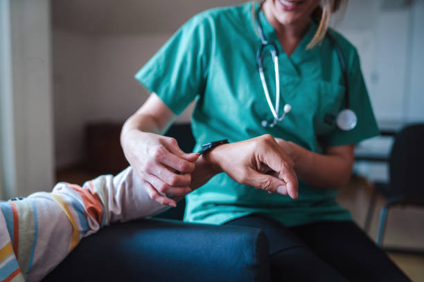smartwatch for health care. a woman from the medical health system wears a smartwatch for remote monitoring of vital signs on an elderly person - assisted living concept - afgelegen stockfoto's en -beelden